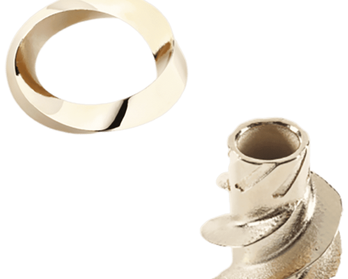 Un anillo de oro liso y un pequeño objeto metálico con ranuras intrincadas, colocados sobre un fondo blanco.