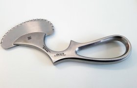 Se coloca un instrumento quirúrgico de acero inoxidable curvado y dentado con un mango ergonómico sobre una superficie blanca.