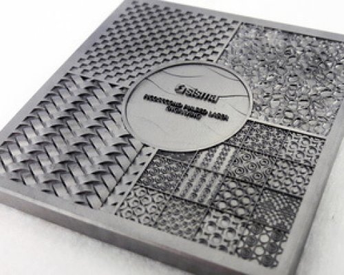 Plato de muestras cuadrado de metal con varios motivos texturados y un círculo central con texto en el centro.