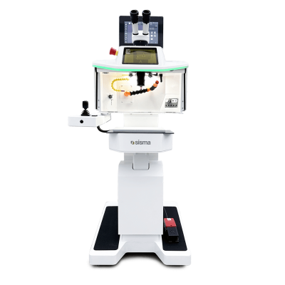 Una máquina de soldadura láser Sisma de color blanco, con pantalla, panel de control, dos oculares de microscopio y un pedal, fotografiada sobre un fondo liso.