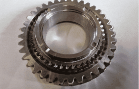Un engranaje de metal de precisión con múltiples dientes y un orificio central se muestra sobre una superficie lisa, ilustrando la intrincada artesanía utilizada en la soldadura láser en la automoción.
