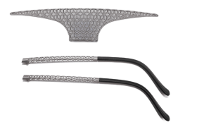 Se muestran dos patillas de gafas geométricas metálicas y un puente nasal a juego, con un patrón tipo panal en el puente y un diseño recto en las patillas.