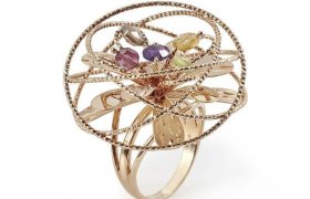 Este intrincado anillo de oro con diseño en espiral presenta cinco piedras preciosas de colores en el centro.