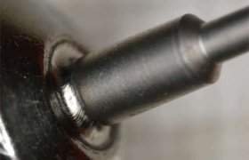 Primer plano de una broca metálica parcialmente insertada en un portabrocas, mostrando finos detalles de las superficies metálicas.