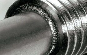 Primer plano de una varilla de metal con un patrón en espiral texturizado alrededor de su sección superior, que muestra una artesanía detallada y un brillo metálico.