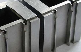 Primer plano de bloques de precisión metálicos con diseño entrelazado sobre una superficie con patrón de cuadrícula.
