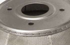 Componente cilíndrico de malla metálica con una abertura circular en la parte superior y orificios más pequeños a su alrededor.