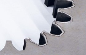 Primer plano de un engranaje de metal con dientes afilados y dentados sobre un fondo simple.