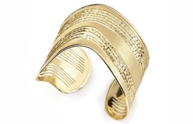 Pulsera de oro con banda ancha, diseño en capas y textura, y extremos abiertos.