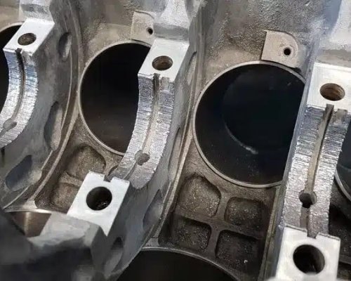Primer plano de la superficie desgastada de un cojinete de motor en el interior de un bloque motor, en el que se aprecian estrías y marcas de desgaste en el metal.