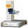 Una máquina de grabado láser compacta con etiqueta "EASY-GO", que presenta una base gris y estructura vertical, y varios botones de control en el panel frontal.