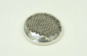 Infusor de té redondo de metal con malla sobre un fondo blanco liso.