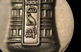 Primer plano de antiguos jeroglíficos egipcios grabados en una superficie metálica, que muestran símbolos que incluyen un pato y una forma similar a un paraguas.