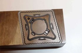 Molde de metal con diseño circular grabado, que presenta el texto “ONU” y el número “12” mostrados sobre una superficie plana.