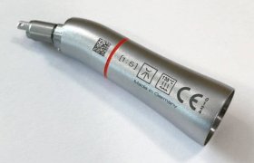 Primer plano de una pieza de mano dental metálica con símbolos grabados y texto "Made in Germany" sobre una superficie blanca.