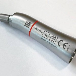 Primer plano de una pieza de mano dental metálica con símbolos grabados y texto "Made in Germany" sobre una superficie blanca.
