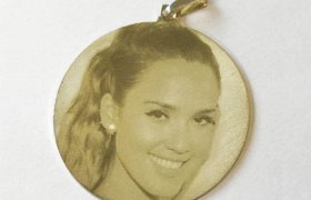 Un colgante circular que presenta la imagen grabada del rostro sonriente de una mujer.