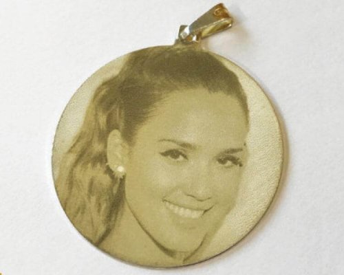 Un colgante circular que presenta la imagen grabada del rostro sonriente de una mujer.