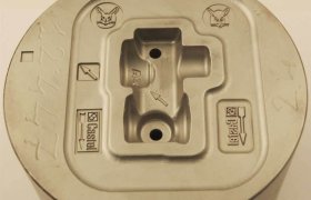 Molde de metal con caras de animales, flechas y números grabados; las características incluyen cavidad elevada y muescas.