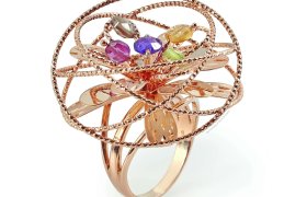 Anillo de oro con un diseño intrincado que presenta varias piedras preciosas de colores colocadas dentro de un patrón circular abierto.