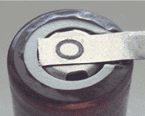 Una herramienta de metal levanta la pestaña de la parte superior de una lata de aluminio sellada, lista para abrirla.