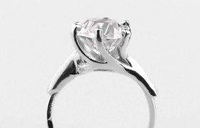 Anillo de plata con un gran diamante de talla redonda engastado en garras, expuesto sobre un fondo liso.