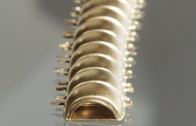 Una fila de objetos semicirculares, metálicos y reflectantes, alineados en diagonal sobre una superficie lisa.