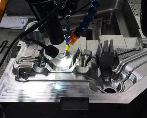 Una máquina CNC realizando un mecanizado de precisión en una pieza metálica, con las mangueras de refrigerante y la herramienta de corte en funcionamiento.