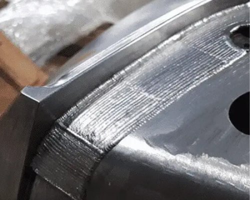Primer plano de una pieza metálica mecanizada con marcas visibles de herramientas y un borde liso en una superficie industrial.