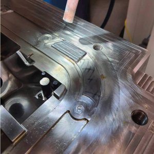 Primer plano de un molde metálico con aspecto desgastado, que muestra una herramienta en el borde superior y varias ranuras y sujetadores visibles en la superficie, marcando un punto de inflexión hacia el futuro de la fabricación.