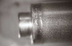 Primer plano de un objeto cilíndrico metálico con una superficie texturizada y una sección central saliente, que muestra una precisión similar a la soldadura láser en la automoción.